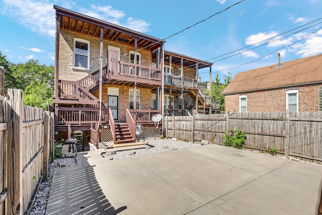 rear view of house featuring a patio, brick siding, a fenced backyard, and stairs