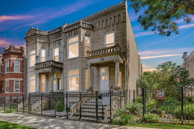 townhome / multi-family property featuring a gate, stone siding, and a fenced front yard