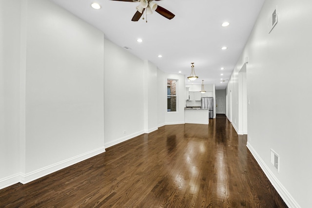 unfurnished living room featuring a ceiling fan, visible vents, baseboards, recessed lighting, and dark wood-style flooring