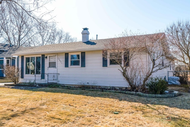 ranch-style home with a front lawn, roof with shingles, and a chimney