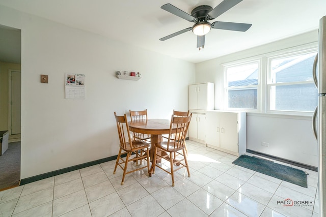 dining area featuring light tile patterned flooring, a ceiling fan, and baseboards