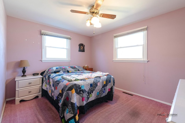 carpeted bedroom featuring visible vents, multiple windows, and baseboards