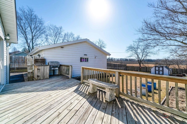 wooden deck with an outdoor structure, area for grilling, a storage unit, and a fenced backyard