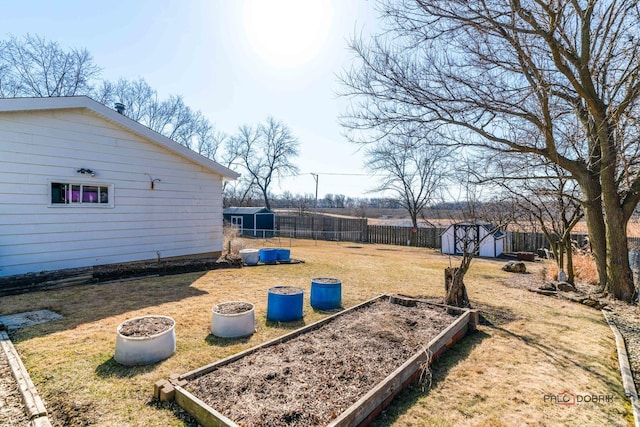 view of yard with an outdoor structure, a garden, a storage unit, and fence