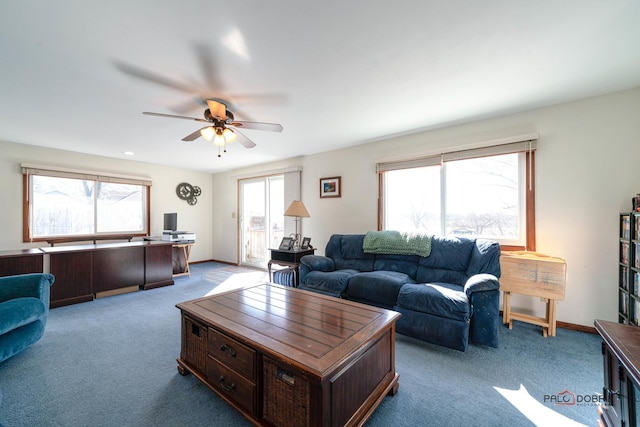 carpeted living area with baseboards and ceiling fan