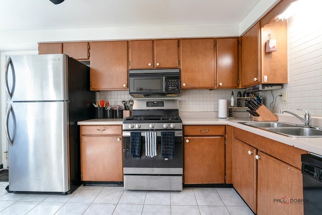 kitchen with black appliances, a sink, backsplash, brown cabinetry, and light countertops