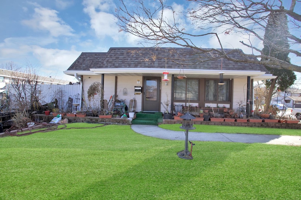 view of front of home featuring a front yard, covered porch, and roof with shingles