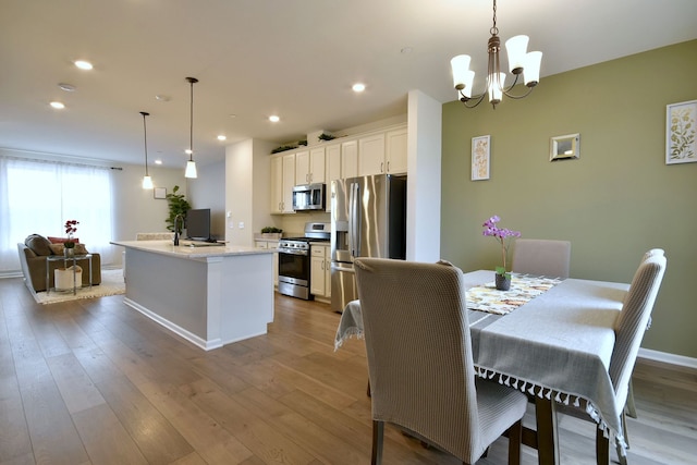 dining area with a chandelier, recessed lighting, baseboards, and wood finished floors