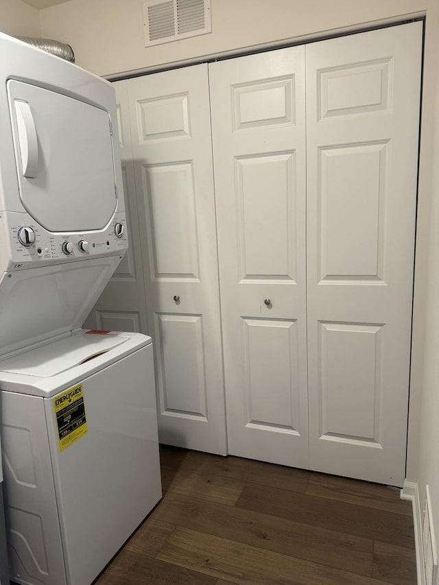 laundry room featuring visible vents, stacked washer and dryer, dark wood-style flooring, and laundry area