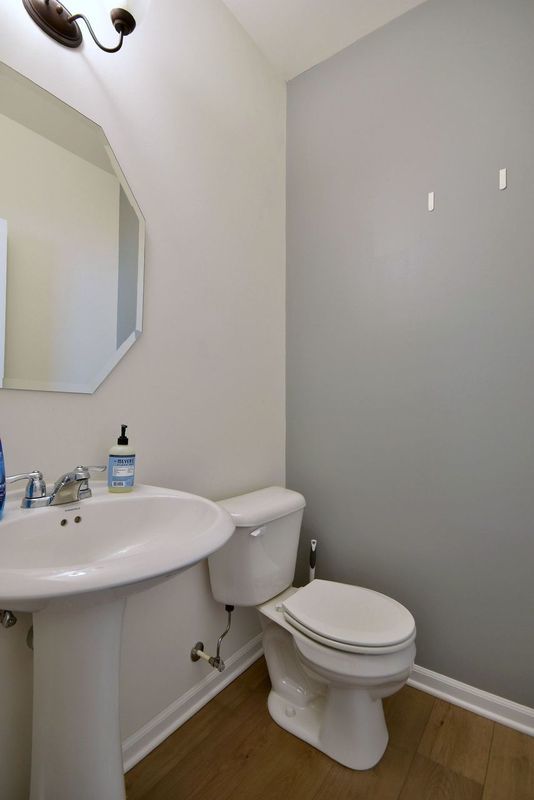 half bathroom with a sink, toilet, baseboards, and wood finished floors