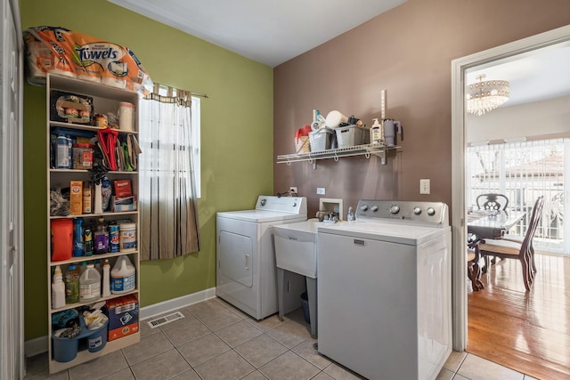 washroom featuring visible vents, laundry area, an inviting chandelier, light tile patterned flooring, and washer and dryer