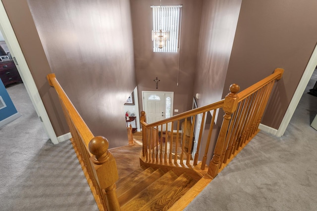 stairway with baseboards, carpet floors, a high ceiling, and visible vents