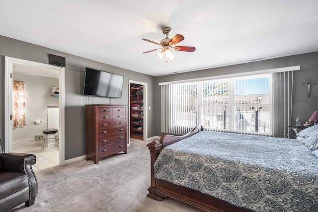 bedroom with baseboards, ceiling fan, a closet, a walk in closet, and light colored carpet