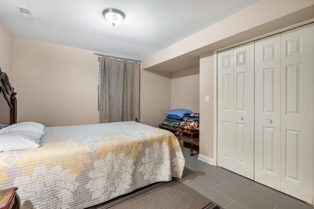 bedroom featuring a closet, visible vents, and dark tile patterned floors