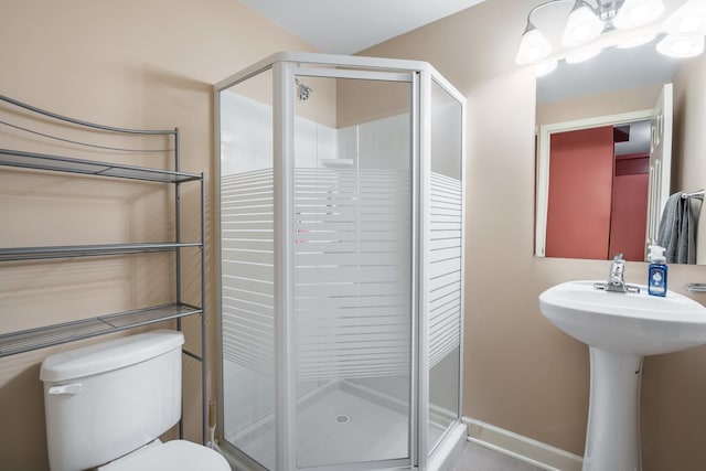 bathroom with a shower stall, toilet, and a sink