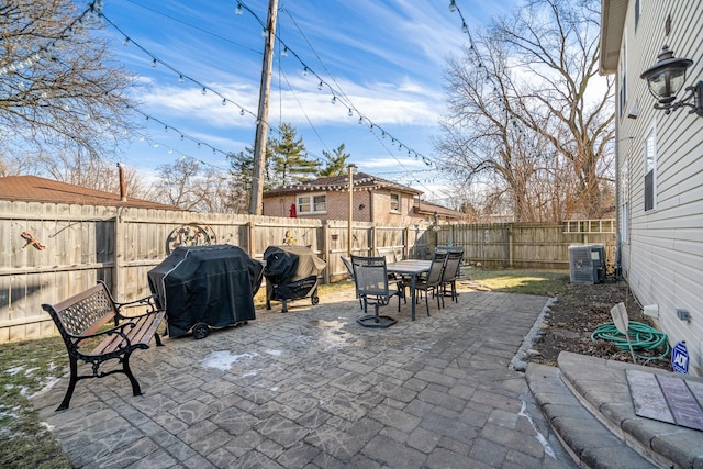 view of patio featuring area for grilling, cooling unit, outdoor dining area, and a fenced backyard