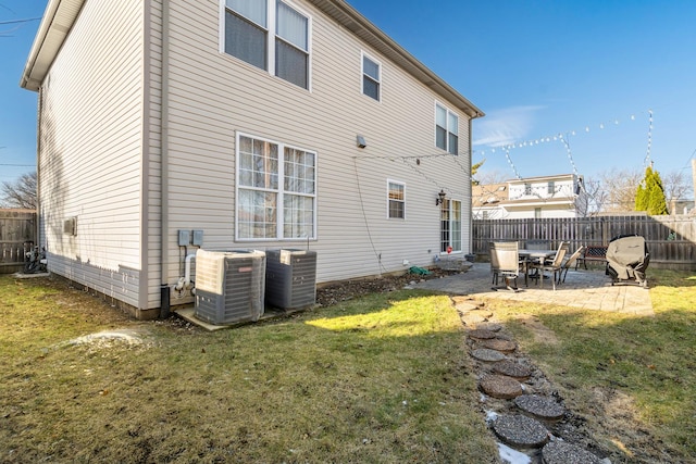 rear view of house featuring a patio area, cooling unit, a fenced backyard, and a lawn