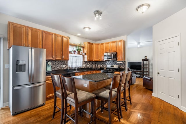 kitchen with stainless steel appliances, backsplash, dark wood-style floors, and a breakfast bar area