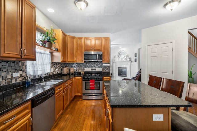 kitchen with decorative backsplash, appliances with stainless steel finishes, a kitchen island, and a sink