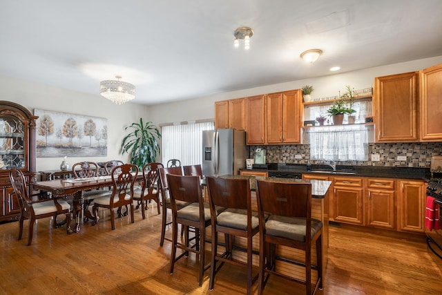 kitchen featuring wood finished floors, open shelves, stainless steel fridge with ice dispenser, a sink, and dark countertops