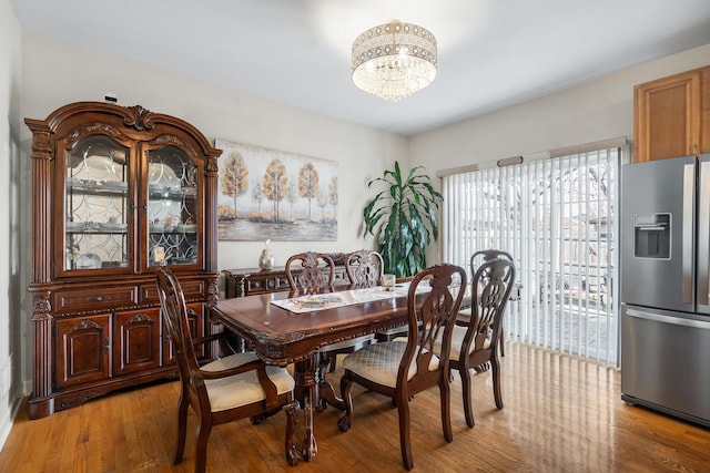 dining area with light wood-type flooring and a chandelier