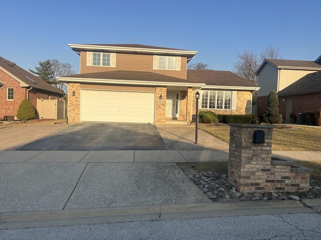 traditional-style home featuring aphalt driveway, brick siding, an attached garage, and fence