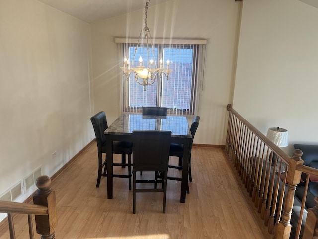 dining space with a chandelier, lofted ceiling, baseboards, and wood finished floors