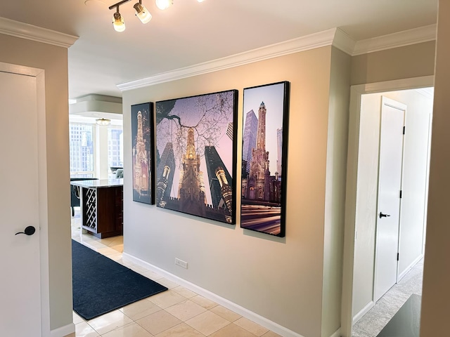 hall featuring light tile patterned floors, baseboards, and crown molding