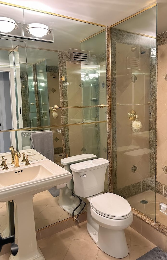 full bath featuring a sink, toilet, a stall shower, and tile patterned flooring