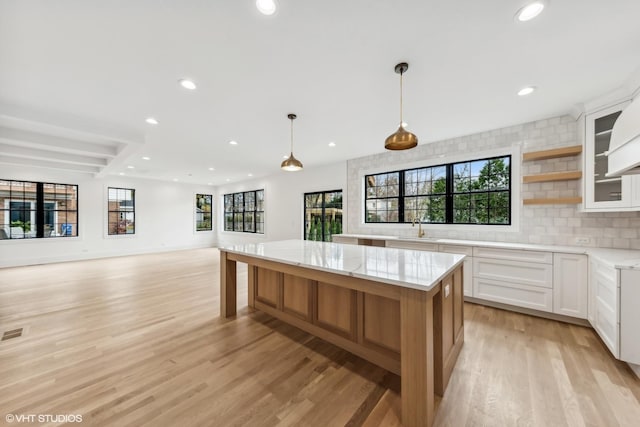 kitchen featuring light wood finished floors, backsplash, a kitchen island, and open shelves