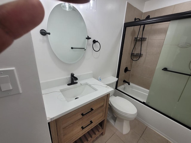 full bathroom featuring combined bath / shower with glass door, toilet, vanity, and tile patterned flooring