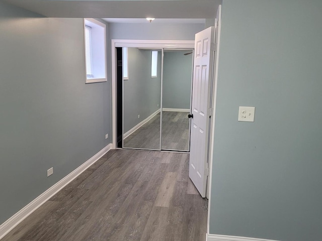 unfurnished bedroom with wood finished floors, baseboards, and a closet