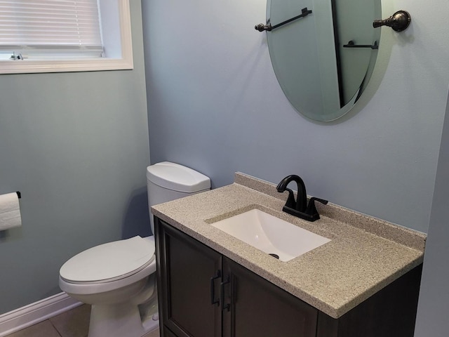 bathroom with toilet, vanity, and tile patterned flooring