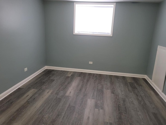 unfurnished room with baseboards and dark wood-style flooring