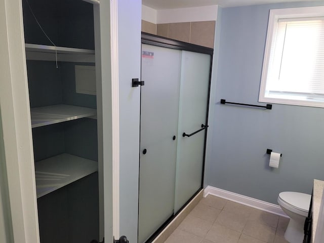 bathroom featuring tile patterned floors, an enclosed shower, toilet, and baseboards