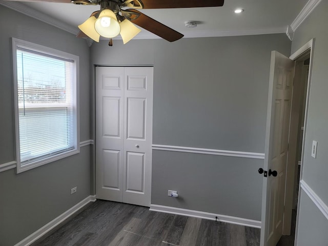 unfurnished bedroom with a ceiling fan, a closet, crown molding, baseboards, and dark wood-style flooring