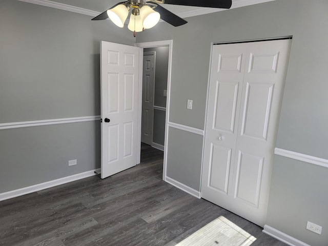 unfurnished bedroom with dark wood-style floors, a closet, crown molding, baseboards, and ceiling fan