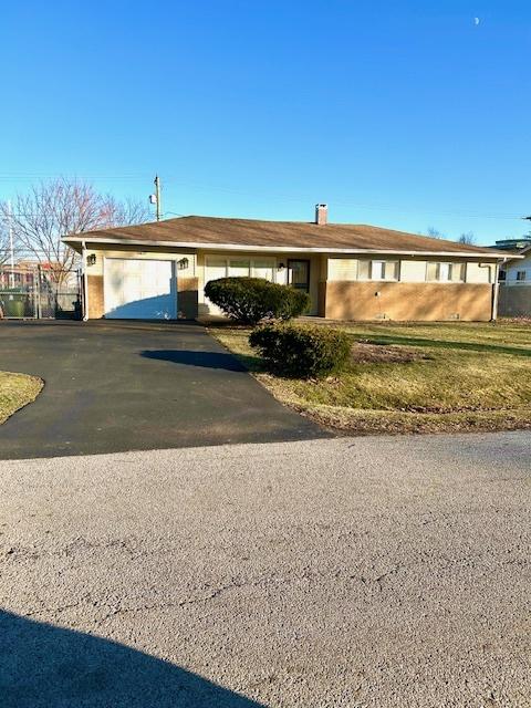 single story home with aphalt driveway, an attached garage, and a chimney