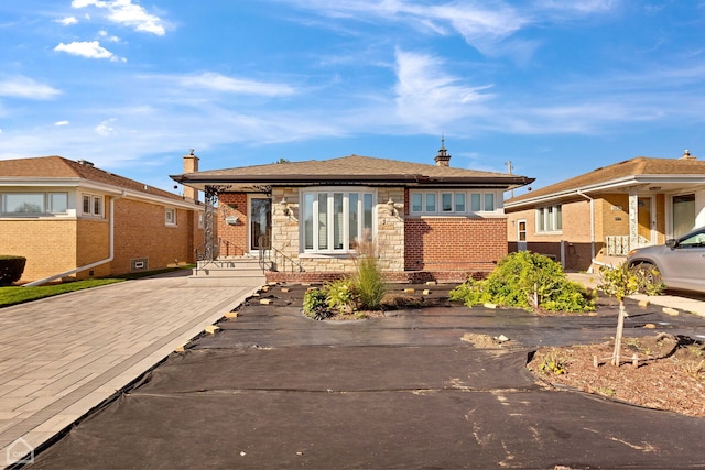 view of front of home featuring stone siding, brick siding, and driveway