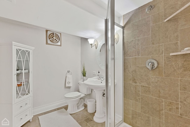 bathroom featuring baseboards, toilet, and a tile shower