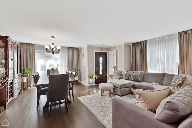 living room with an inviting chandelier, baseboards, dark wood-style flooring, and ornamental molding