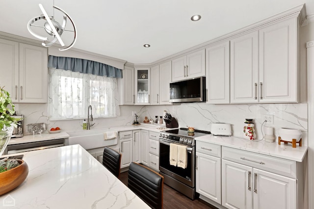 kitchen with decorative backsplash, appliances with stainless steel finishes, light stone countertops, and a sink