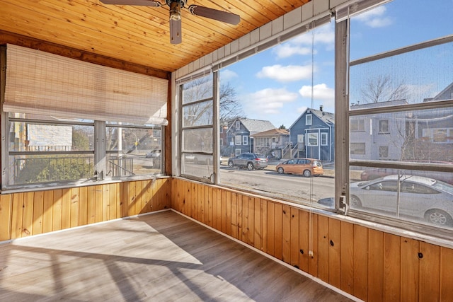 unfurnished sunroom featuring a residential view, ceiling fan, and wooden ceiling