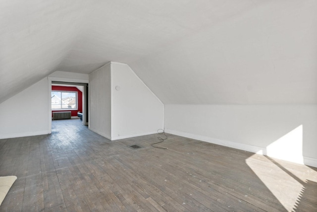 bonus room featuring visible vents, radiator, baseboards, lofted ceiling, and hardwood / wood-style flooring