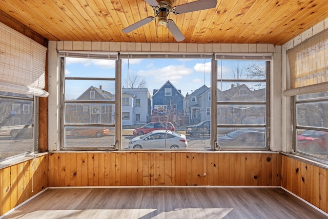 unfurnished sunroom with a ceiling fan, wood ceiling, and a residential view