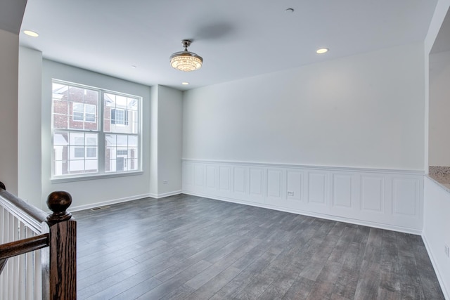 empty room featuring recessed lighting, visible vents, dark wood-style floors, and wainscoting