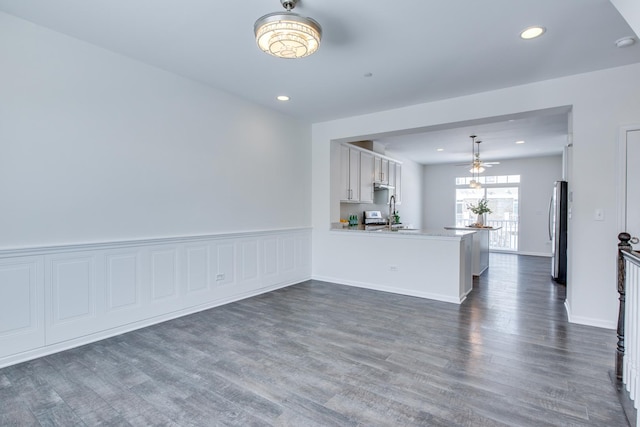 unfurnished living room with recessed lighting, dark wood-style floors, wainscoting, and a sink