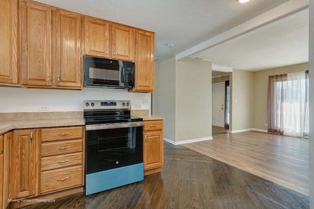 kitchen featuring light countertops, stainless steel range with electric stovetop, dark wood-style flooring, and black microwave