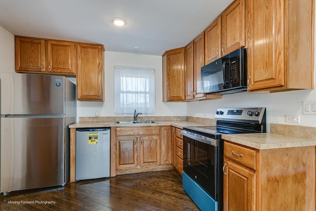 kitchen featuring brown cabinets, a sink, dark wood-style floors, stainless steel appliances, and light countertops