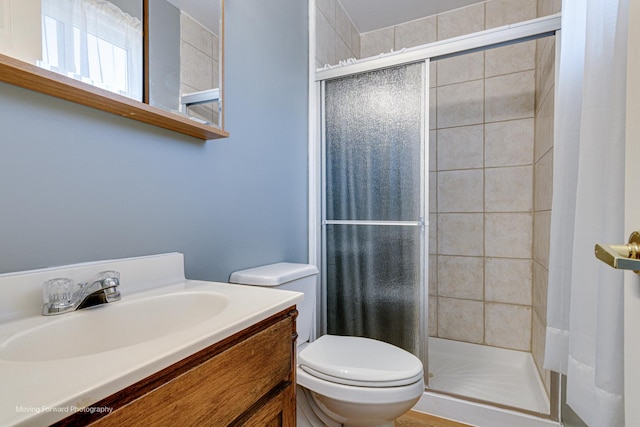 full bath with vanity, a shower stall, and toilet